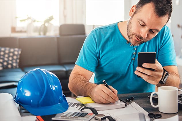Man looking at phone and writing